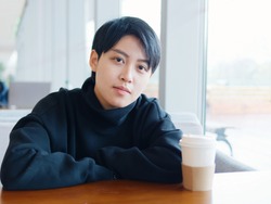 Portrait of cute beautiful young lesbian with short haircut and trendy boyish clothes sitting in coffee shop, friendly Chinese gay girl.