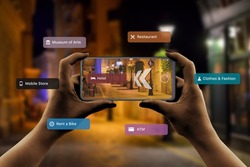 Finding hotels and other tourist facilities in the city with 3d navigation app based on augmented reality technology concept. Phone in  women hands. City street at night