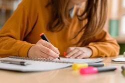 Young unrecognisable female college student in class, taking notes and using highlighter. Focused student in classroom. Authentic Education concept.