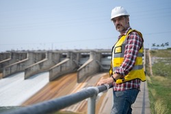 Portrait of engineer wearing yellow vest and white helmet Working day on a water dam with a hydroelectric power plant. Renewable energy systems, Sustainable energy concept