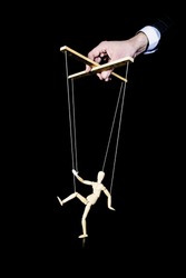 Puppeteer. The hand controls the puppet strings on a black background. Dancing wooden puppet. Manipulation of the people.