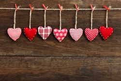 Gingham Love Valentine's hearts natural cord and red clips hanging on rustic driftwood texture background, copy space