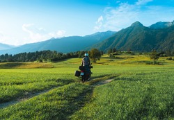 Man motorcyclist ride touring motorcycle. Alpine mountains on background. Biker lifestyle, world traveler. Summer sunny sunset day. Green hills. hermetic packaging bags. Slovenia