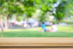Empty wooden picnic table over blurred park and people background, for product display montage
