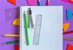School stationery on violet background. Colorful math fractions, rulers, open notepad on a purple background. Interesting, fun math for kids. Education, back to school concept