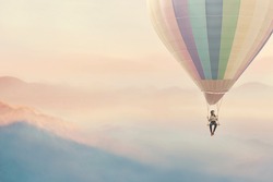surreal woman enjoying herself on a swing hanging from a hot air balloon