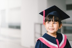 Portrait of a cute Asian graduated schoolgirl with graduation gown in school