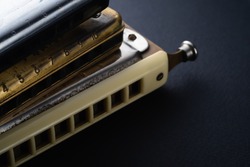 the old two diatonic and one chromatic harmonica, one on top of the other on a dark background. Horizontal orientation.