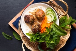 Food concept Bun Cha Vietnamese rice noodles and Meatballs with vegetables and herbs on black background with copy space