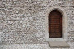 Heavy closed door on a stone wall of a medieval fortress, made of riveted wood