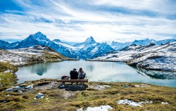 Unknown  couple on wood bench over Bachalpsee  lake landscape  above Grindelwald.