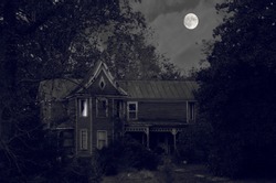 Creepy old house in black and white hidden in the forest with a full moon background and a possible ghost in the upstairs window