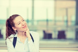 Portrait happy young woman thinking dreaming has many ideas looking up isolated office windows background. Positive human face expression emotion feeling reaction. Decision making process concept