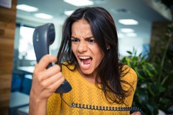 Angry businesswoman shouting on phone in office