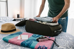 Man packing his suitcase in the bedroom at home. Travel vacation and holidays concept