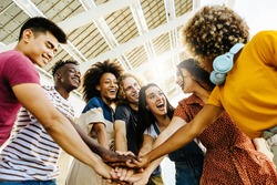 Multiracial happy friends with hands in stack. Multi-ethnic diverse group of college students joining their hands. Stacking hand concept, community, unity and teamwork concept - Focus on afro woman