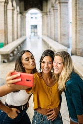 Vertical shot of young happy group of multiracial best women friends taking selfie photo on cellphone outdoor during summer vacation in Italy - Travel and female friendship concept