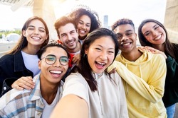 Diverse group of happy young best friends having fun taking selfie photo together - International youth community people concept with multiethnic teenage people smiling at camera on self portrait