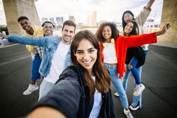 Multiracial young group of trendy people having fun together on vacation - Diverse millennial friends taking selfie portrait together while enjoying free time on city street - Friendship concept