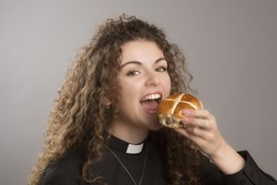 Young priest eating Hot Cross buns a tradition at Easter time