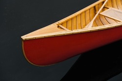 Bow (nose) of a red canadian canoe. Wood canoe boat on dark water