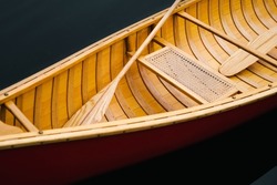 Details of a beautiful wooden canoe boat on the water. Paddles and seat of a boat floating on dark water, no people