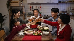 cheerful chinese family with mixed generation raising glasses to toast new year as they are gathering to have reunion dinner in celebration of spring festival chinese new year at home