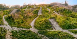 There are many different paths and directions through dangerous uneven terrain. Winding paths and routes on green hills