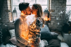 A guy with a girl is celebrating Christmas. A loving couple enjoys each other on New Year's Eve in a cozy home environment. New Year's love story.