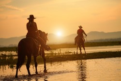 horseback riding from behind overlooking wide open field and mountains 
