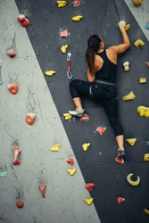 Active sporty woman practicing rock climbing on artificial rock in climbing s. Extreme sports and bouldering concept.