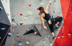 Sporty successful business woman being busy at her hobby-bouldering. Well equipped woman training in a colorful climbing gym, preparing to summer mountain ascend