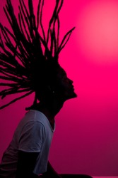 silhouette of african man with flying dreadlocks in profile on red background