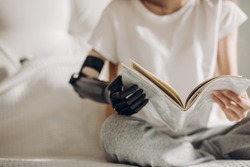 woman's artificial arm holding a book, close up photo. blurred image.normal life with a prosthetic limb