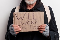 Unrecognizable homeless man holding sign, request for job, seeking help posing at studio over white background