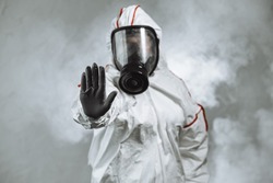 keep the distance, stop to coronavirus. disinfector male in gas-mask and protective suit disinfect contaminated areas full of bacterias. quarantine time