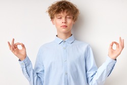 teenager caucasian boy in shirt relax and doing meditation gesture with fingers. yoga concept
