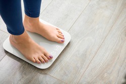 Close-up photo of woman legs stepping on floor scales indoors, space for text. Overweight problem