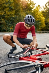 Sportsman bicycle cyclist repair parts and adjusting by himself on the road. outdoors. strong athlete guy in sportswear and helmet is engaged in healthy lifestyle, sport training on bike