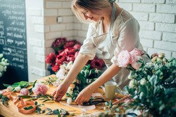 Small business. Male florist unfocused in flower shop. Floral design studio, making decorations and arrangements. Flowers delivery, creating order