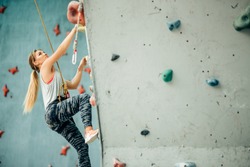 Free climber young woman climbing artificial boulder indoors
