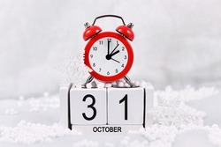 Time change for daylight saving winter time in Europe on October 31st concept with red alarm clock and calendar in snow