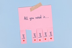Tear off stub note with text 'All you need is love' on pink paper