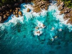 Aerial view Top down seashore. Waves crashing on rock cliff. Beautiful dark sea surface in sunny day summer background Amazing seascape top view seacoast at Intendance Beach, Mahe Seychelles