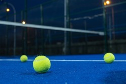 Selective focus. Three paddle tennis balls on the surface of a blue paddle tennis court. Sports concept.