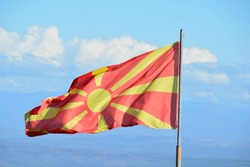 Northern Macedonia's red and yellow colored flag in wind against the blue and cloudy sky