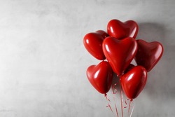 Heart shaped foil balloons on concrete wall background