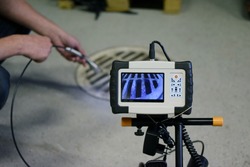 Man start using sewer inspection camera. Monitor showing picture from camera head that inspector is holding.