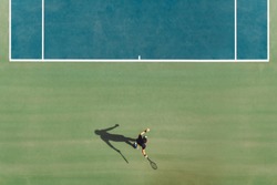 Aerial view of young male tennis player playing on hard court. Professional tennis player hitting a forehand on court.