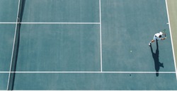 Aerial view of young tennis player playing on hard court. Professional tennis player hitting a backhand on court.